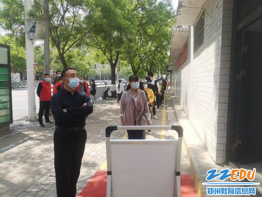 3教师间隔排队等待进入测温室