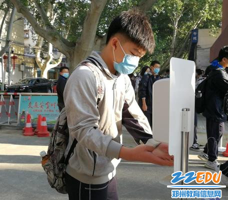 学生利用手部消毒器快速消毒进校