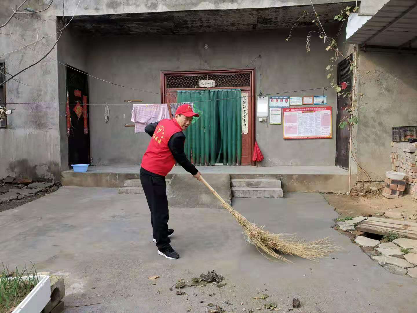 总务主任高中亮帮助村民打扫院子卫生