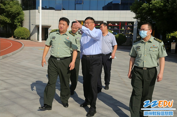 1郑州市第十九高级中学党委书记、校长梁寅峰（中）向中国人民解放军联勤保障部队第九八八医院院长谢峻（左一）介绍硬件设施。_副本
