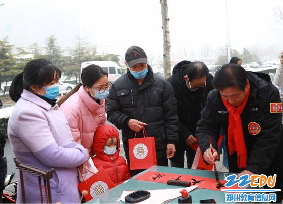 家长和幼儿驻足观看现场写春联 家长和幼儿驻足观看现场写春联