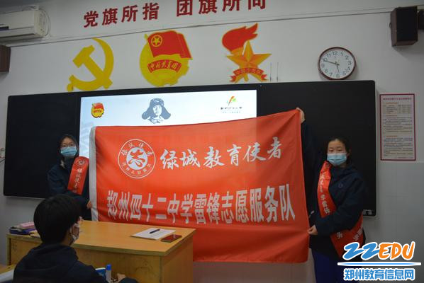 4 学生展示“绿城教育使者”郑州42中学雷锋志愿服务队的旗帜