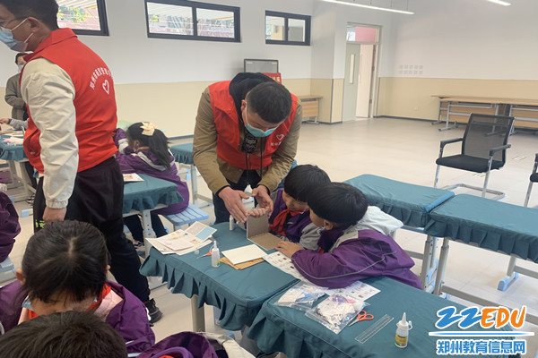 郑州市商贸管理学校团委副书记李蒙帮同学粘模型墙壁_副本 郑州市商贸管理学校团委副书记李蒙帮同学粘模型墙壁_副本