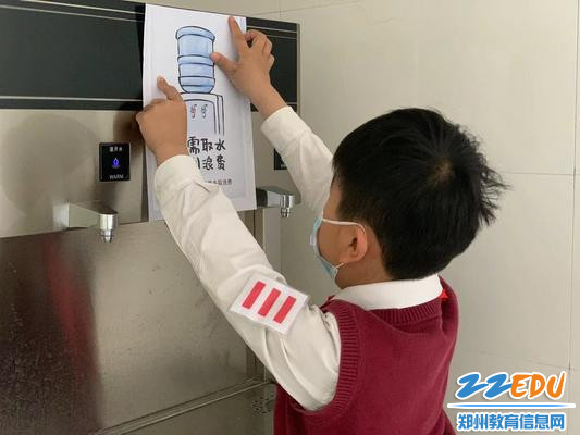 学生们在校园饮水机旁张贴节水宣传标语