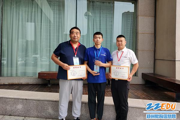 2022年国赛一等奖获得者贾永生同学（左二）和两位辅导教师李瑾来（左一）、张兴远（右一）手持奖杯和证书合影