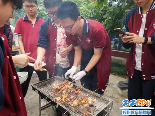 学生有模有样地给铁板上的鸡翅、羊肉串上油