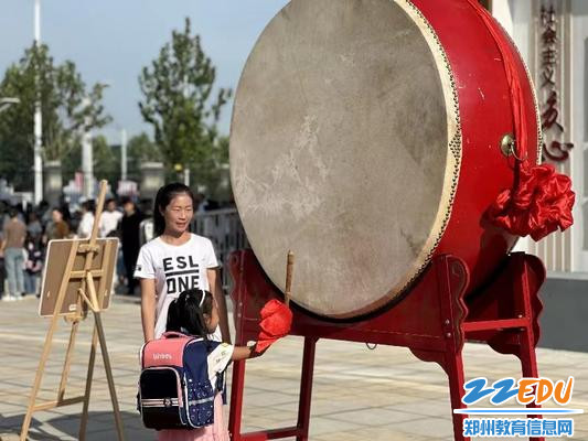 郑州航空港区实验学校的学生走过拱门敲响旁边大鼓，击鼓三下 (2)