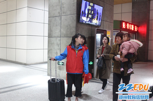 志愿者帮助带小孩的老人提行李