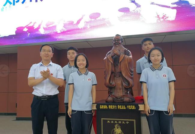 5.学生代表向母校捐赠至尊先师孔子像，郑州八中学区副学区长张广伟代表学校接受捐赠，并与学生合影