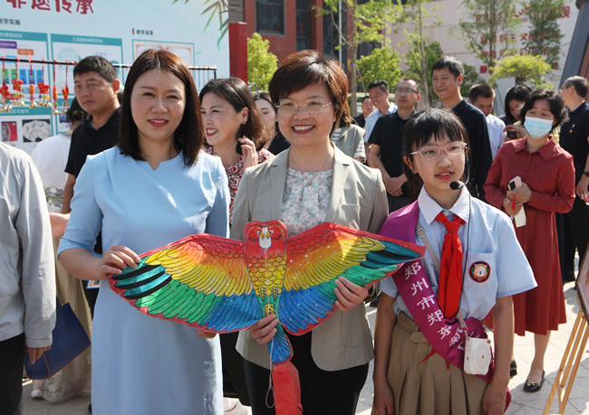 郑州市教育局党组书记、局长王丽娟观看学生作品，并合影。