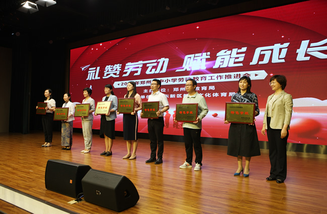 郑州市教育局党组书记、局长王丽娟为获得首批郑州市中小学劳动教育特色学校代表颁奖。