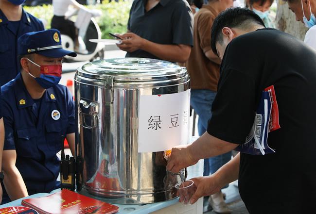 郑州市中原区消防救援大队消防员为考生家长提供绿豆水、扇子等便民服务